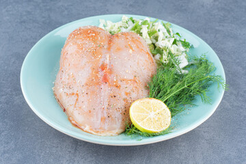 Chicken fillet and lemon on blue plate