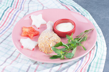 Raw chicken drumstick and mayonnaise on pink plate