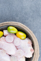 Raw chicken legs with vegetables on dark plate