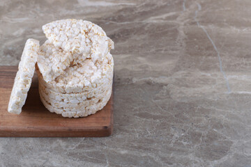 A stack of puffed rice cakes on the wooden tray, on the marble background