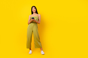 Full length portrait of gorgeous positive thai girl hold telephone look empty space isolated on...