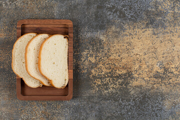 Tasty white bread slices on wooden plate
