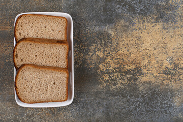 Three slices of black bread on white square plate