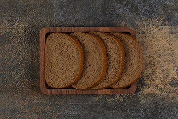 Sliced black bread on wooden plate