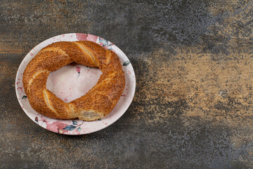 Delicious simit with sesame seeds on colorful plate