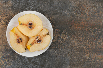 Slices of yellow quince on white plate