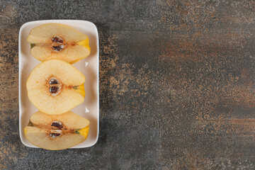 Slices of yellow quince on white square plate
