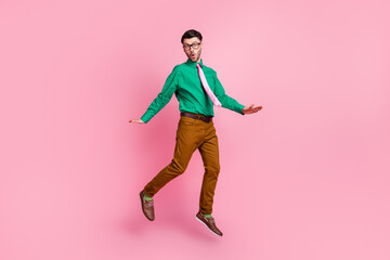 Full length photo of funny impressed guy wear green shirt spectacles jumping high isolated pink color background
