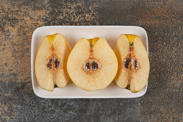 Slices of yellow quince on white square plate
