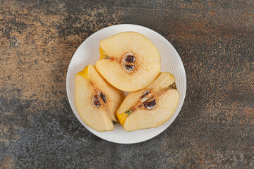 Slices of yellow quince on white plate
