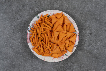 Dried bread cheese flavored cone shaped corn chips in plate , on the marble background