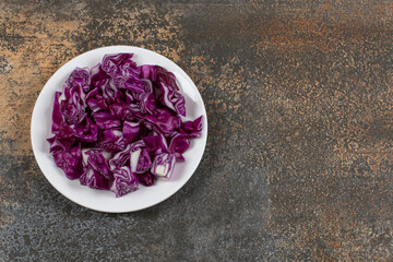 Grated red cabbage in the bowl, on the marble background