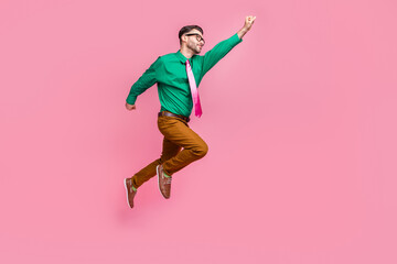 Fototapeta na wymiar Full length photo of excited purposeful guy wear green shirt spectacles jumping high rising hist empty space isolated pink color background