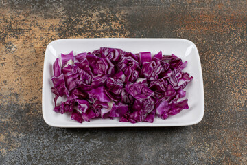 Grated red cabbage in the bowl, on the marble background