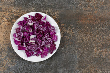 Obraz na płótnie Canvas Finely chopped red cabbage in the plate, on the marble background