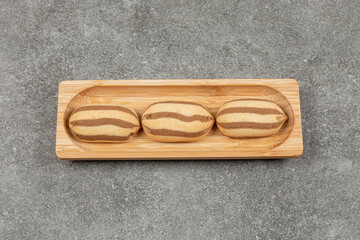 Delicious chocolate striped biscuits on wooden plate
