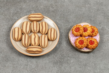 Plate of chocolate striped biscuits and jelly biscuits on marble surface