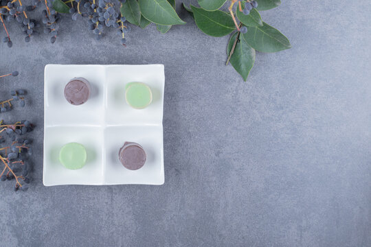 colorful macaroons on white white plate over grey background
