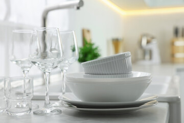 Fototapeta na wymiar Different clean dishware and glasses on countertop in kitchen