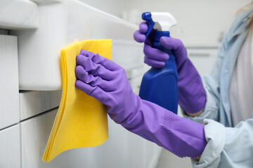 Woman cleaning white surface with rag and detergent indoors, closeup
