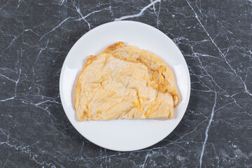 Single omelette on the plate , on the marble background
