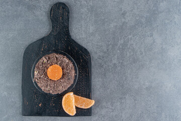 Chocolate cake with orange jelly candy on a dark board