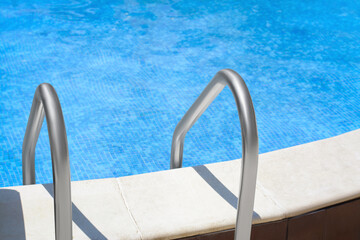 Obraz na płótnie Canvas Swimming pool with metal ladder on sunny day