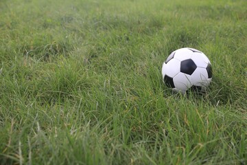 Dirty soccer ball on green grass outdoors, space for text
