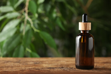Bottle of essential oil on wooden table against blurred background, space for text - obrazy, fototapety, plakaty