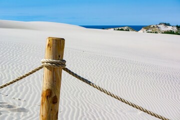 Wooden and rope fence at Leba sand desert in Poland with sea - obrazy, fototapety, plakaty