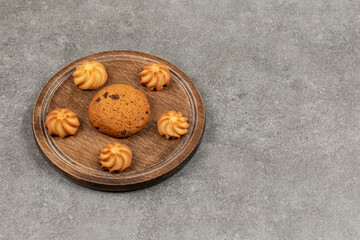 Single chocolate cookie and biscuits on wooden board