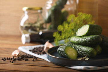 Fresh cucumbers and other ingredients prepared for canning on wooden table, closeup. Space for text