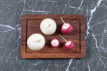 Whole red and white turnips on wooden board