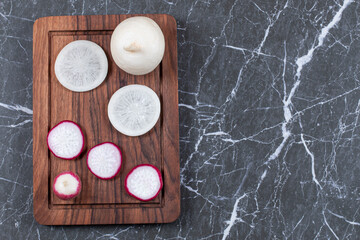 Obraz na płótnie Canvas Sliced red and white turnips on wooden board