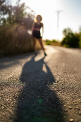 Shadow of athletic woman on the road in nature