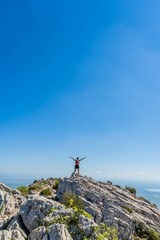 Fototapeta premium Victorious happy woman with arms in the air on top of a mountain