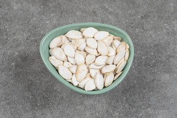 Tasty pumpkin seeds in blue bowl