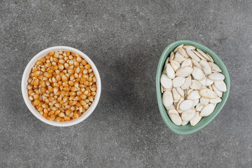 Tasty pumpkin seeds in blue bowl and corn kernels
