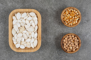 Tasty pumpkin seeds, corn kernels and peas on marble background