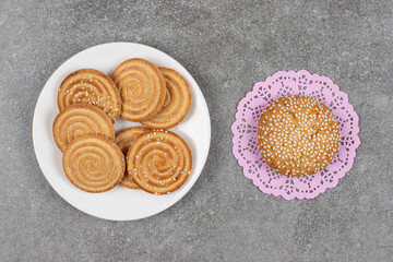 Crunchy biscuits with seeds on white plate with fresh bun