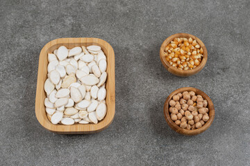 Tasty pumpkin seeds, corn kernels and peas on marble background