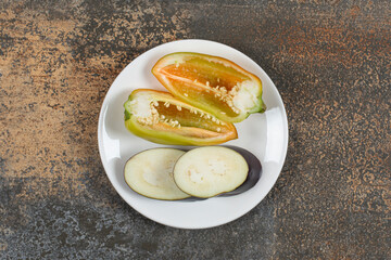Aubergine and pepper in the plate , on the marble background