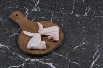 Raw chicken wings on the board, on the marble background