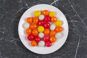 Colorful candies in the plate, on the marble background