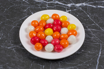 Colorful candies in the plate, on the marble background