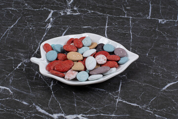 From each other delicious candies in the bowl, on the marble background