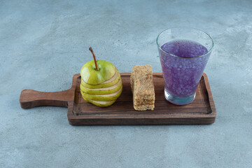 Sliced green apple with purple drink on a wooden board