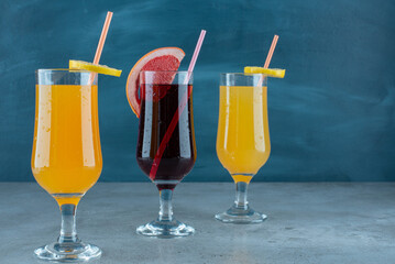 Three various juices in glass cups with straw