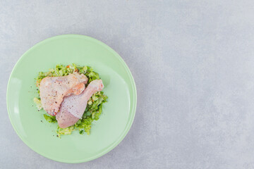 Two marinated chicken legs in the plate, on the white background