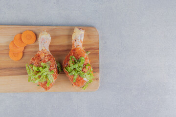 Obraz na płótnie Canvas Sliced carrot and chicken leg on the cutting board, on the white background